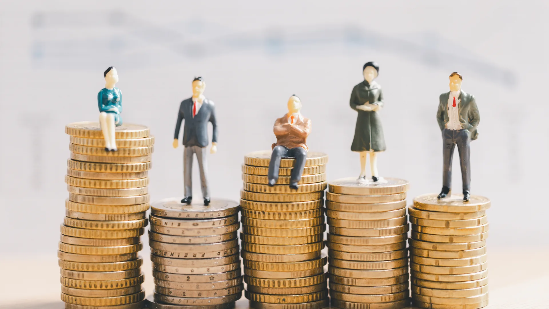 Five stacks of gold coins with miniature figures of people on each stack.